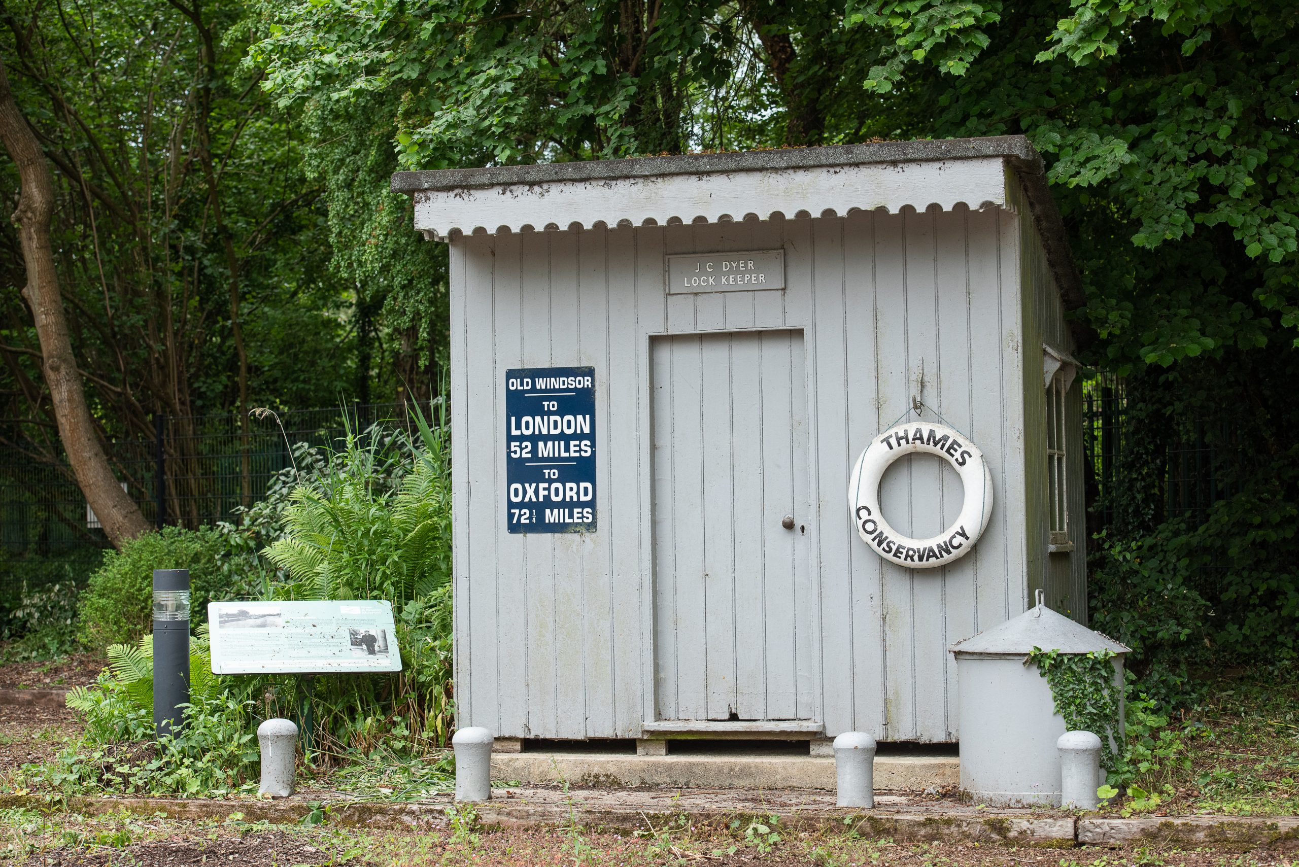 A greay lock keeper's shed with a buoy hanging next to the door